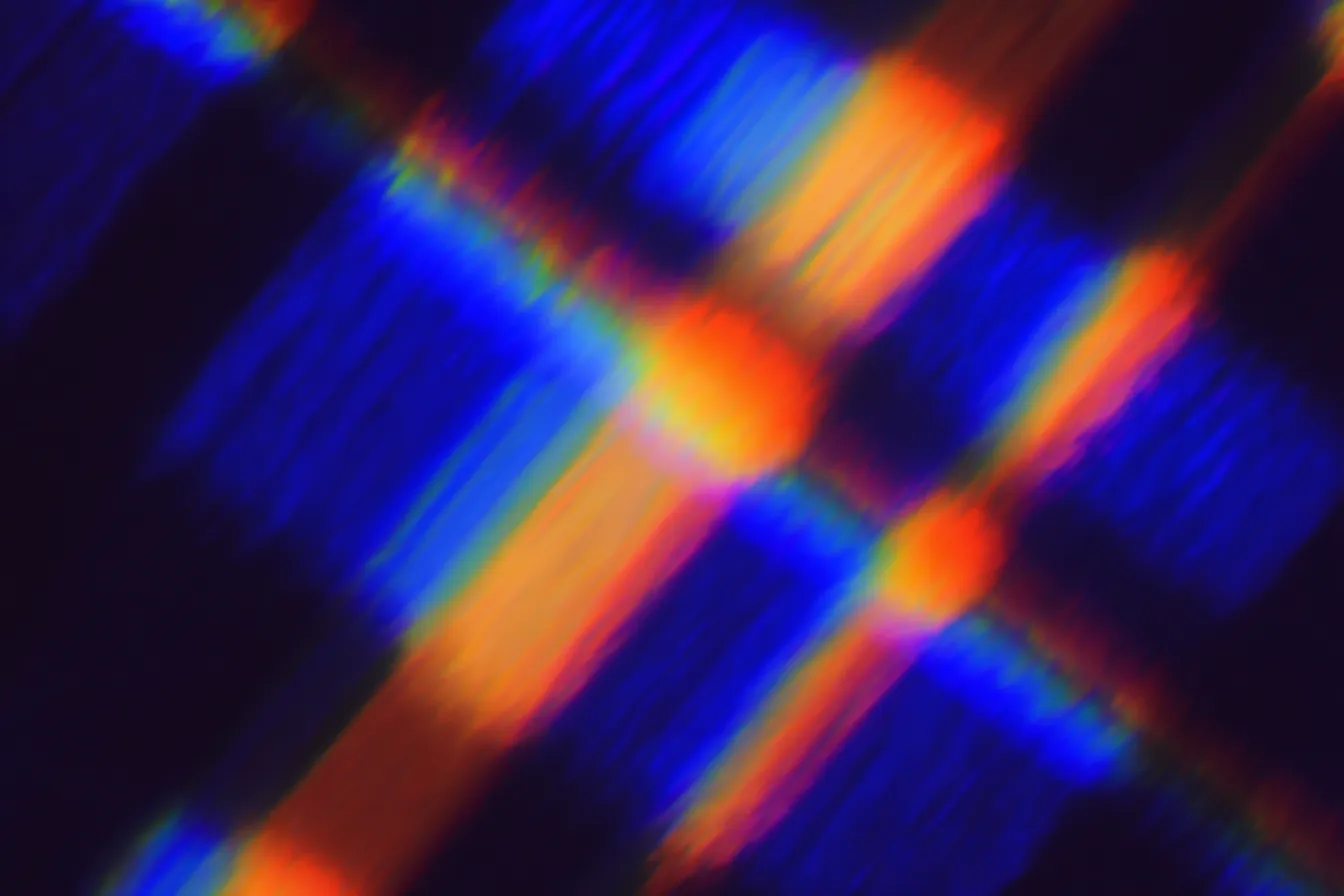 Textura abstracta con patrón de cuadros tipo tartán en azul oscuro y franjas diagonales naranjas y rojas, con un punto de luz circular anaranjado en el centro.