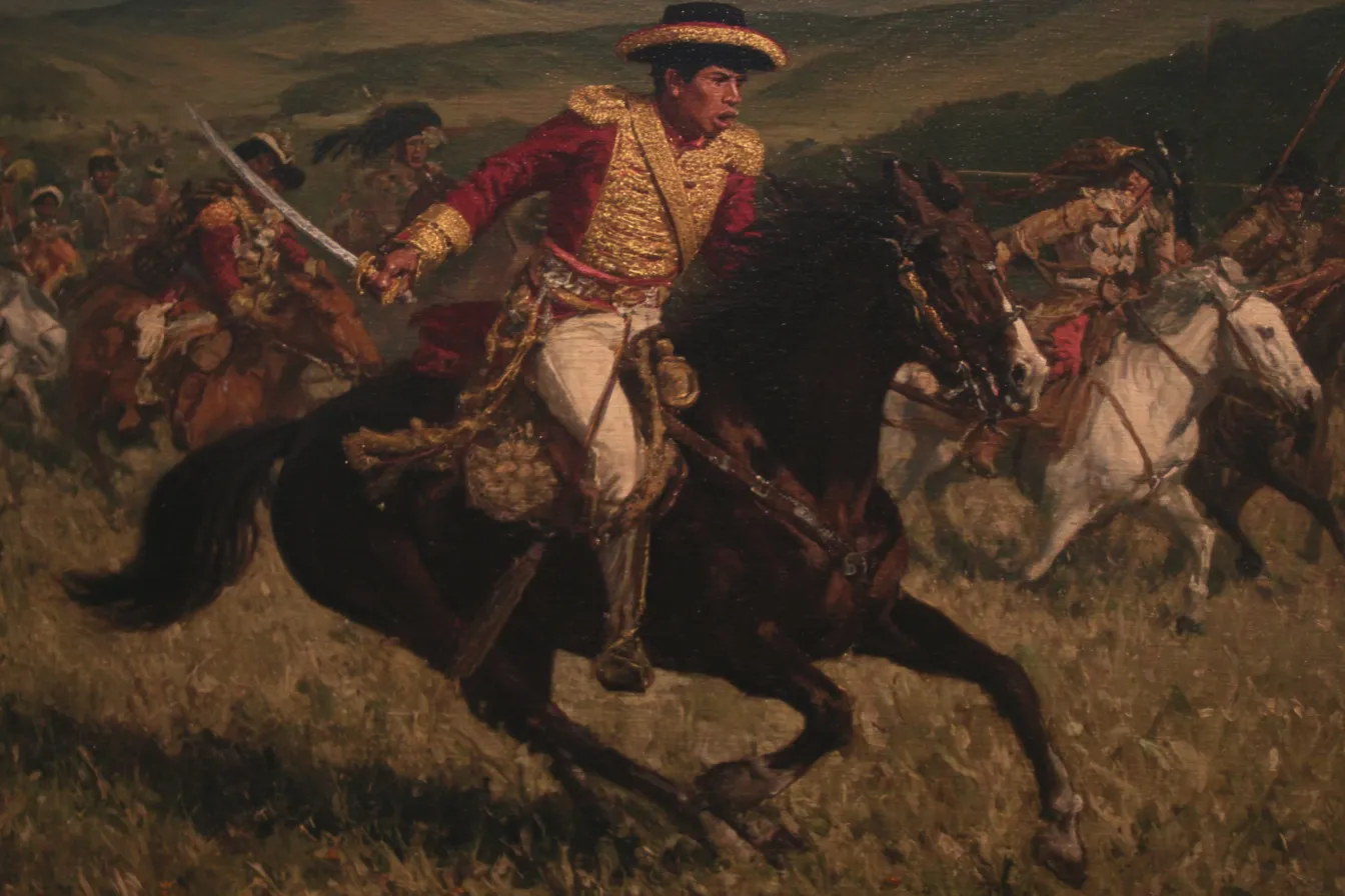 Un jinete con uniforme militar rojo y dorado carga a caballo con un sable en alto, seguido por otros jinetes con casacas rojas, sobre un campo abierto en tonos ocres.