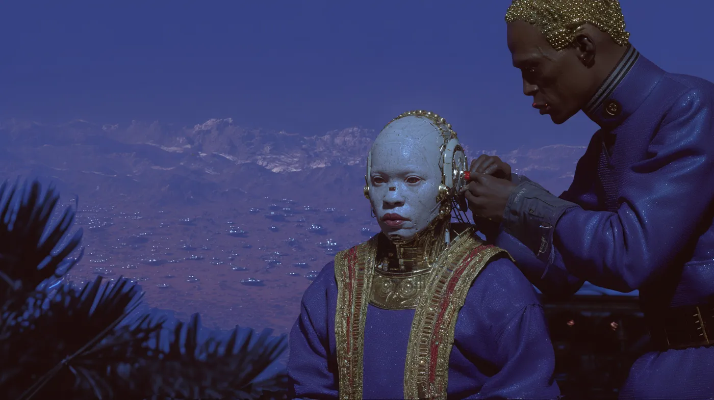 Una persona de pie con túnica azul oscura bordada en dorado y tocado ornamentado ajusta el cabello de otra persona sentada, de piel pálida azulada y cabeza rapada, frente a un paisaje montañoso brumoso de tono azul.