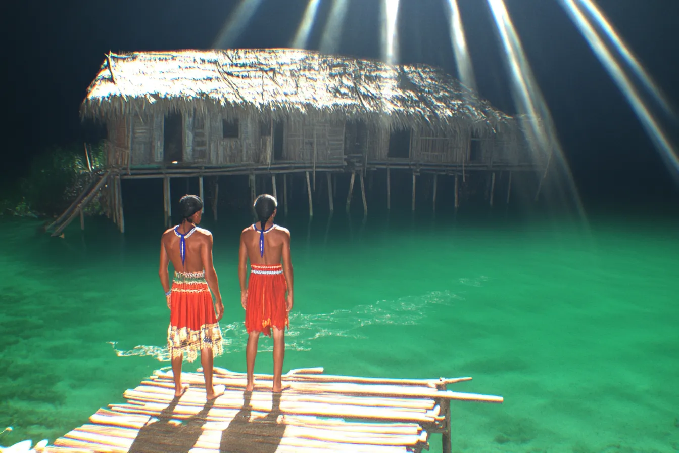 Dos personas vestidas de rojo están de pie sobre un muelle de madera de noche, iluminadas por un haz de luz vertical, frente a una casa de techo de paja sobre el agua verde brillante.