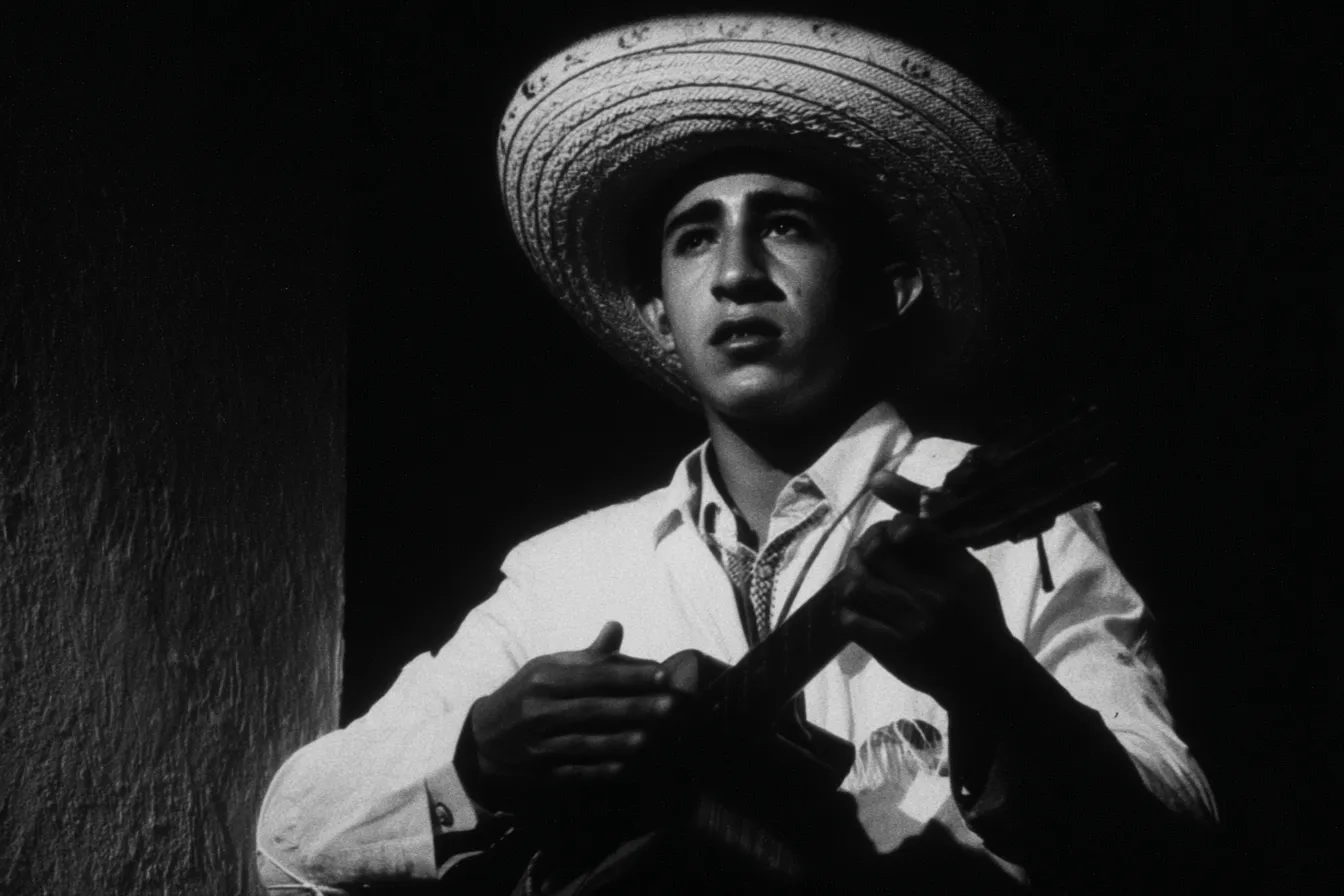 Hombre joven con sombrero de ala ancha toca un cuatro en una fotografía en blanco y negro, con luz lateral fuerte contra un fondo oscuro.